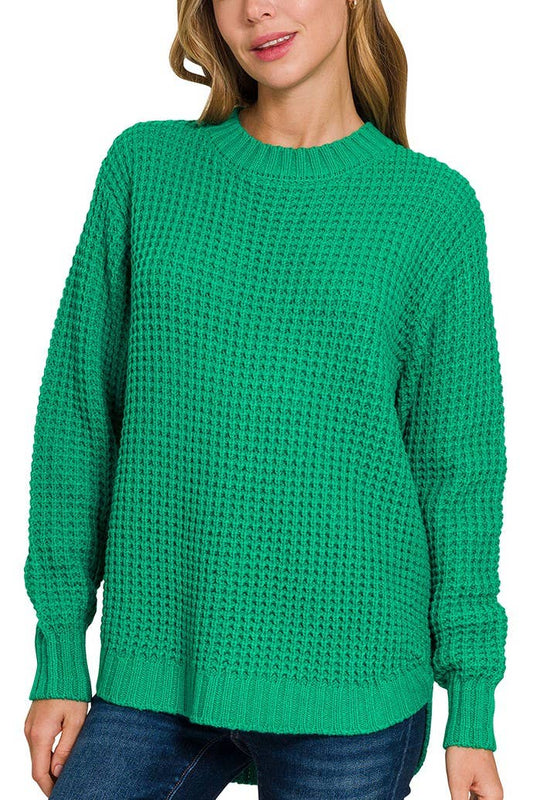 Green knitted sweater worn by a person on a white background