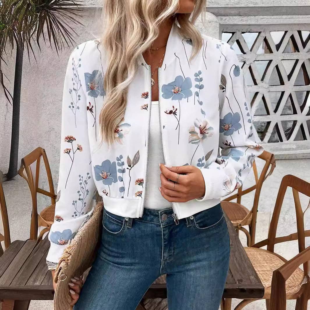 Woman wearing a floral bomber jacket and blue jeans outdoors.