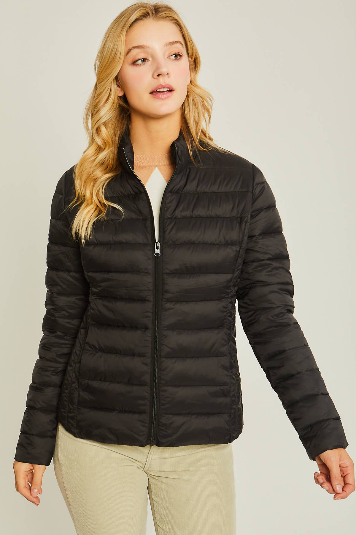 Woman wearing a black puffer jacket on a plain background