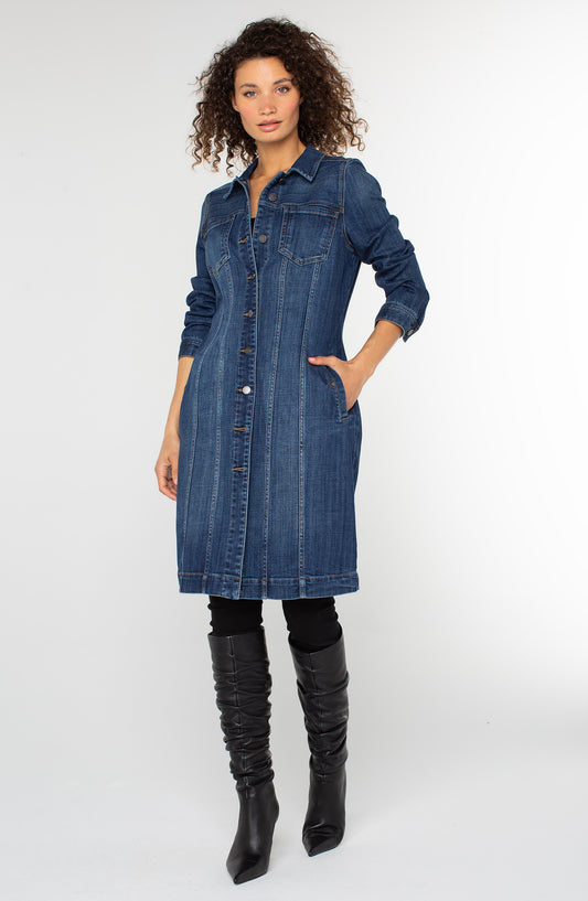 Woman wearing a denim dress with black knee-high boots on a white background